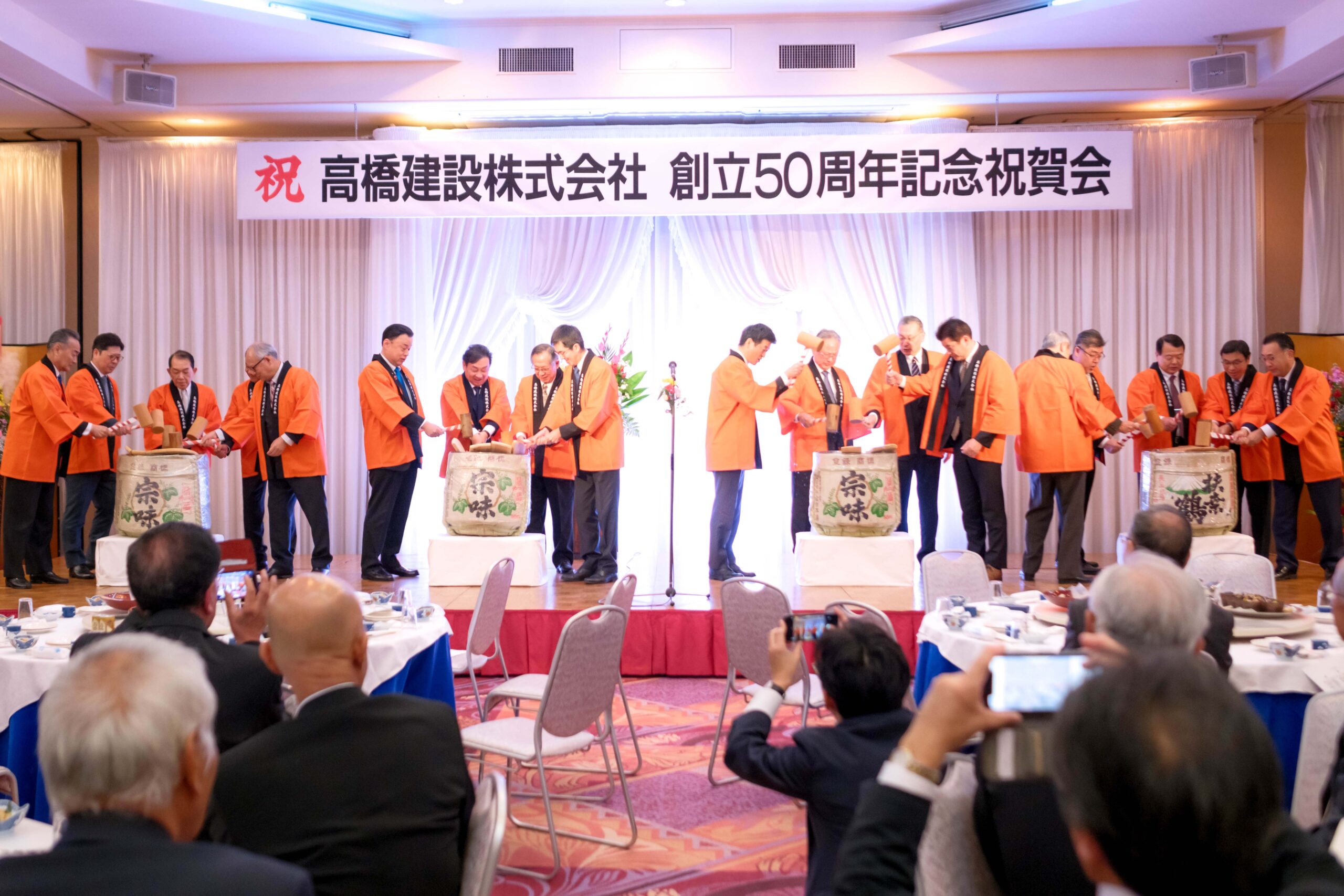 alt=“高橋建設 創業50周年祝賀会で鏡開きの様子”